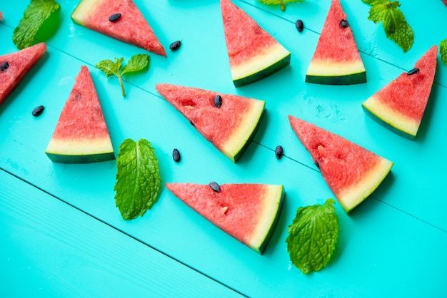 Watermelon slice with mint leaves on blue table