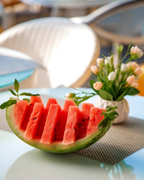 Watermelon sliced into pieces and a vase of flowers