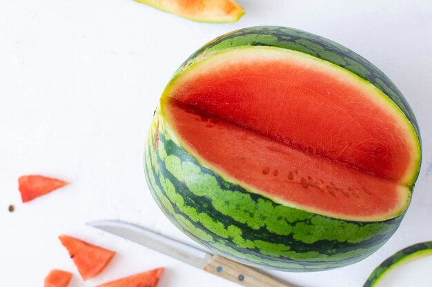 Watermelon with knife on white table