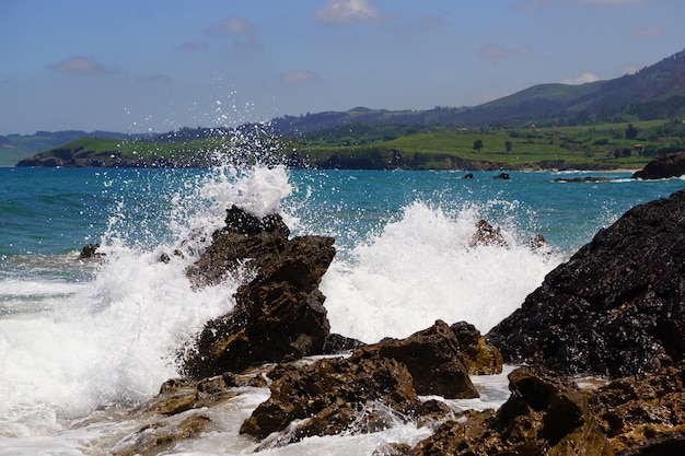 Waves breaking onto rocks with a blue ocean behind them