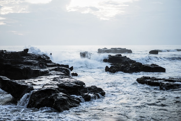 the waves of the ocean are breaking against the rocks. splashing ocean waves at sunset.