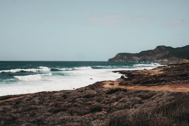 Wavy ocean with rock formations under the blue sky