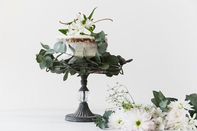 Free photo wedding cake on cakestand decorated with white flower bouquet