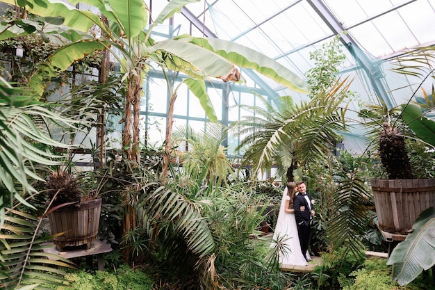 Wedding Couple Hugging In Garden With Many Plants