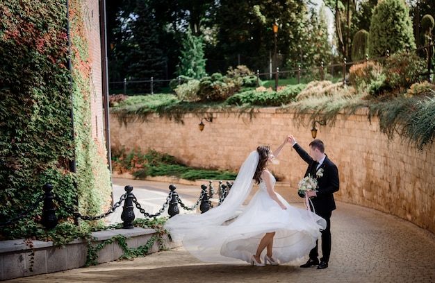 Free photo wedding couple is dancing near stone wall covered with green ivy