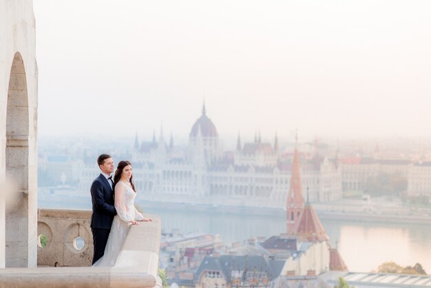 Wedding couple on the stone balcony of an old historical building with breathtaking view of Budapest