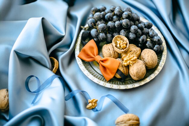 Wedding decorations with grapes and nuts in a plate side view on a blue cloth background