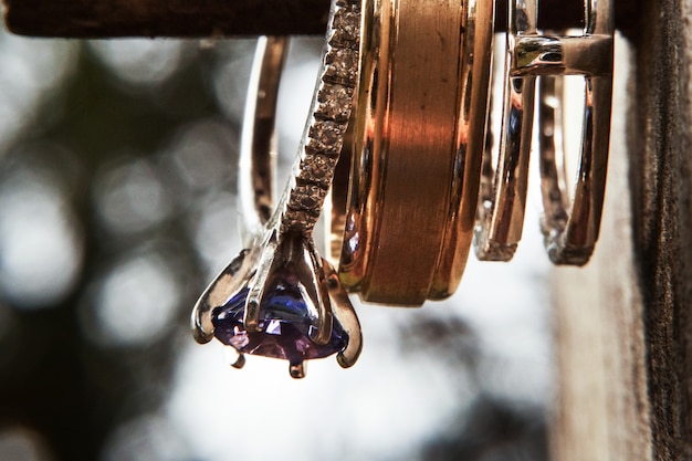 Wedding and engagement rings hang on a stick 