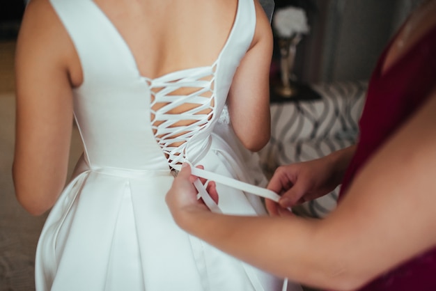 Free photo wedding preparations. helping the bride to put her wedding dress on.