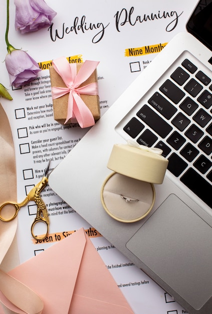 Wedding ring on laptop and invitation papers