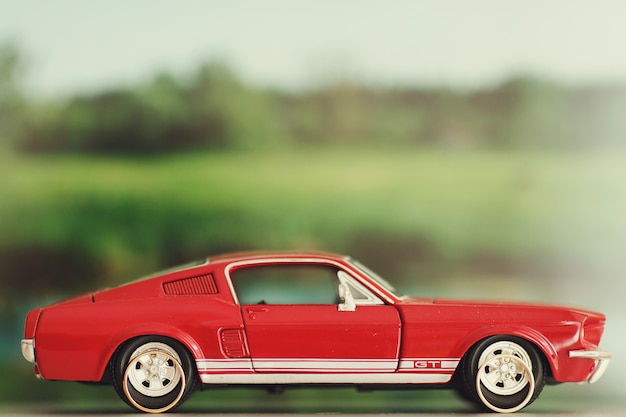 Free Photo wedding rings lie behind the wheels of a toy red mustang 