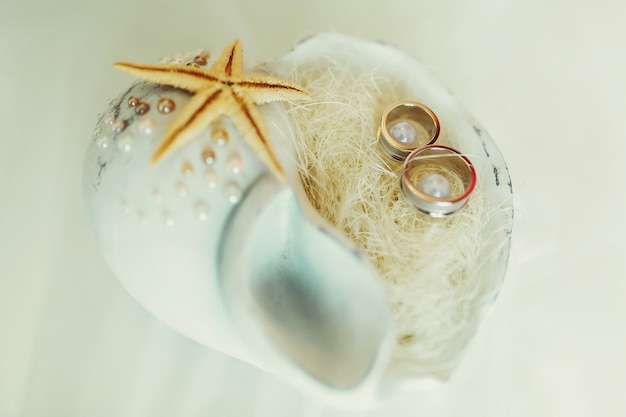 Free photo wedding rings lie in a white cockleshell with little pearls