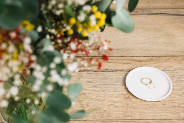 Free Photo wedding rings with bouquet of flowers