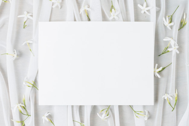 Free photo wedding white placard surrounded with jasminum auriculatum flowers on scarf