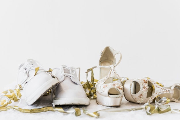 Wedding white shoes and elegance high heel with golden streamers on white background