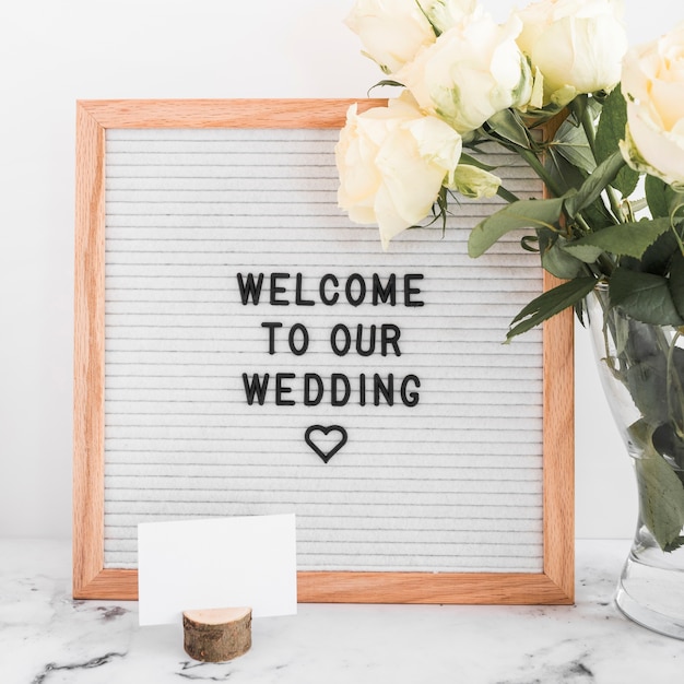 Welcome to our wedding message on wooden frame with blank visiting card and roses