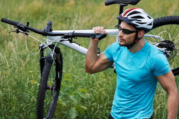 Free photo well built man carrying his bike