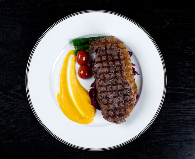 Free photo well-done steak with cherry tomato and asparagus