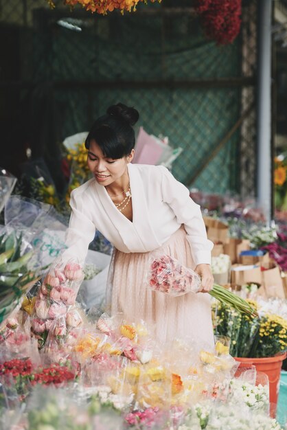 Well-dressed Asian lady choosing flowers in florist shop