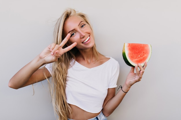 Well-dressed happy woman holding slice of watermelon.