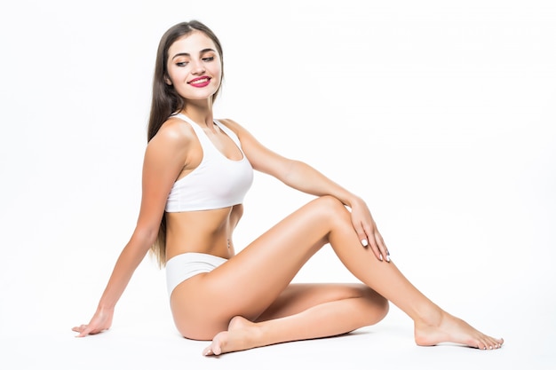 Wellness and beauty concept. Beautiful slim woman in white underwear sitting on white floor