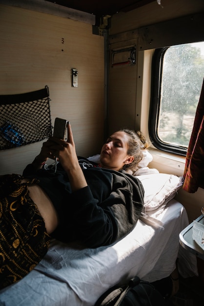 Free photo western female backpacker using her phone in the indian train