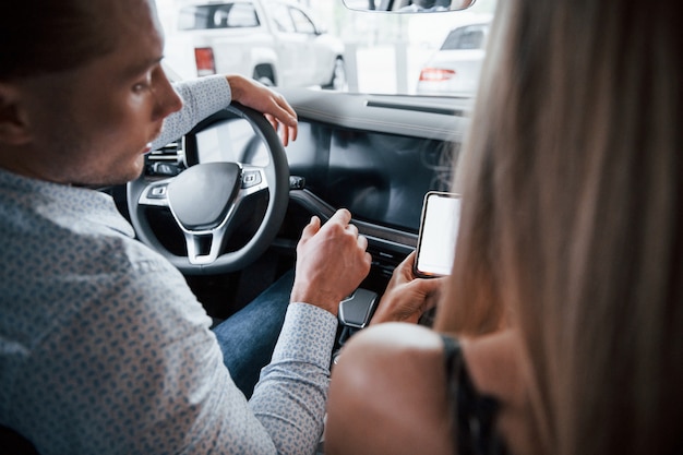 Where we gonna go. Positive manager showing features of the new car to female customer