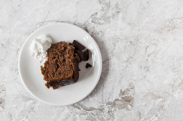 Whipped cream and slice of cake on plate over the marble counter