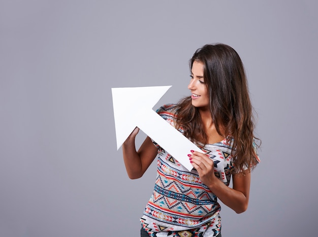 Free photo white arrow sign held by attractive young woman