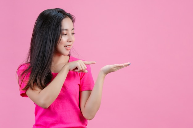 White asian woman The right hand pointed to the left hand that was holding the right hand. On a pink .