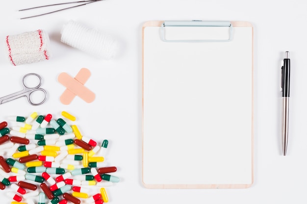 White blank clipboard with pen and medical supplies and equipments on white background