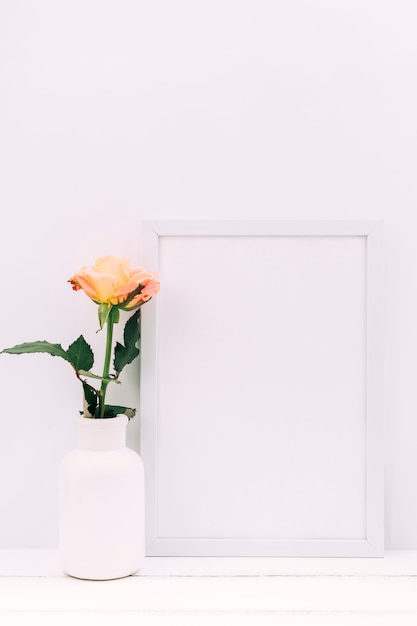 Free Photo white blank frame and fresh rose on wooden table