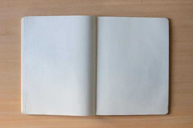 White blank opened copybook with a lot of space of text on a wooden background