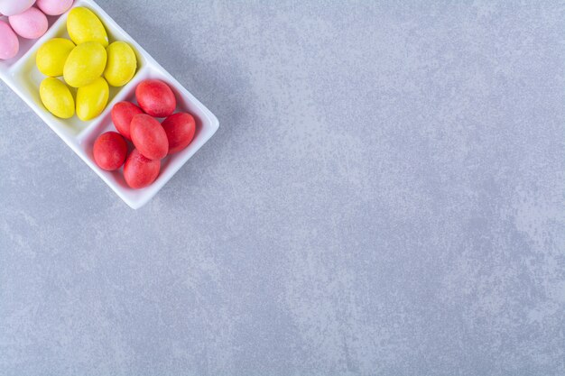 A white board full of colorful bean candies on gray table. 