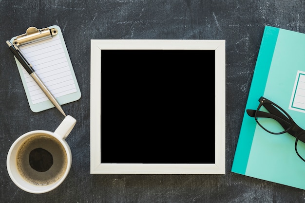 White border picture frame; coffee cup and stationeries on blackboard