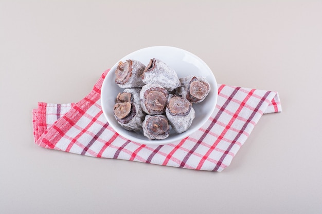 White bowl full of dried persimmons on white background. High quality photo