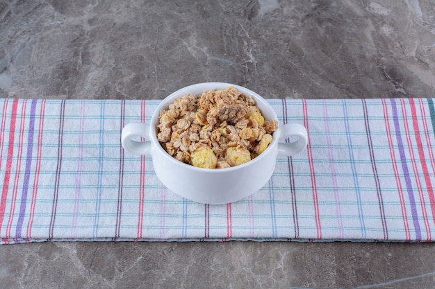 A white bowl full of tasty healthy cornflakes on tablecloth . 