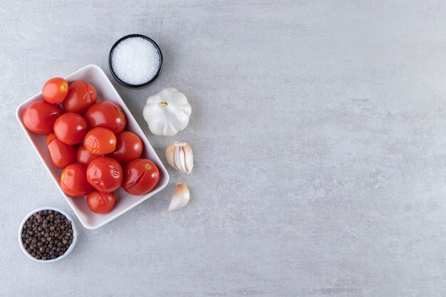 Free photo white bowl of pickled tomatoes placed on stone background.