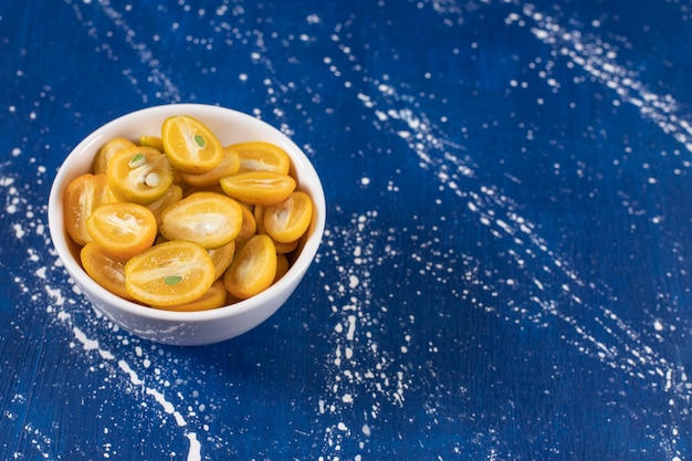 Free Photo white bowl of sliced kumquat fruits on marble surface