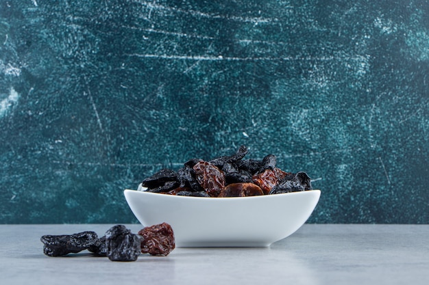 White bowl of tasty dried dates on stone background.