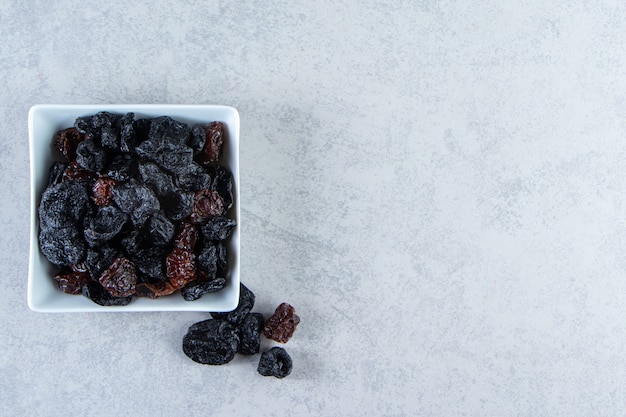 White bowl of tasty dried dates on stone.