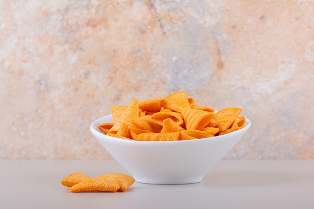 White bowl of triangle chips on marble background. High quality photo