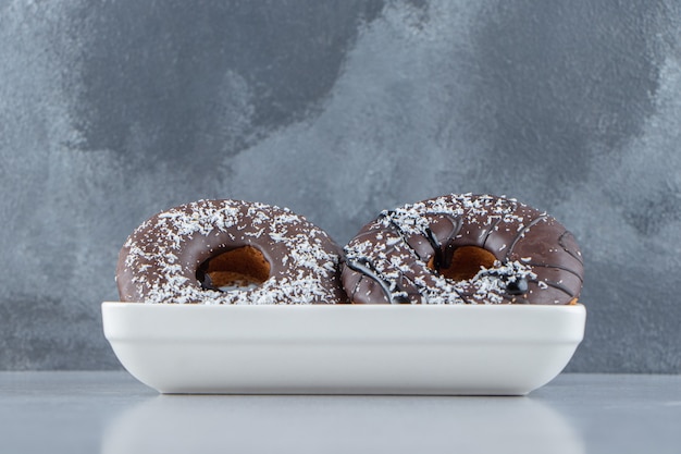 Free photo white bowl of two chocolate donuts on stone background. high quality photo