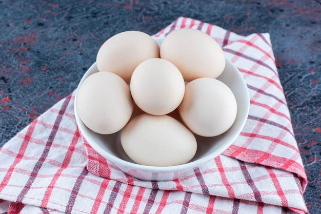 A white bowl with fresh raw chicken eggs 