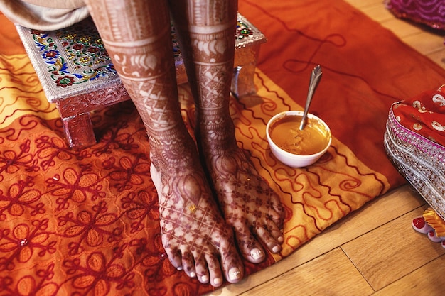 White bowl with turmeric paste stands beneath Indian bride