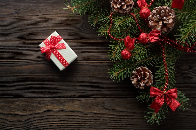 White box with a red bow on a wooden table with christmas ornament