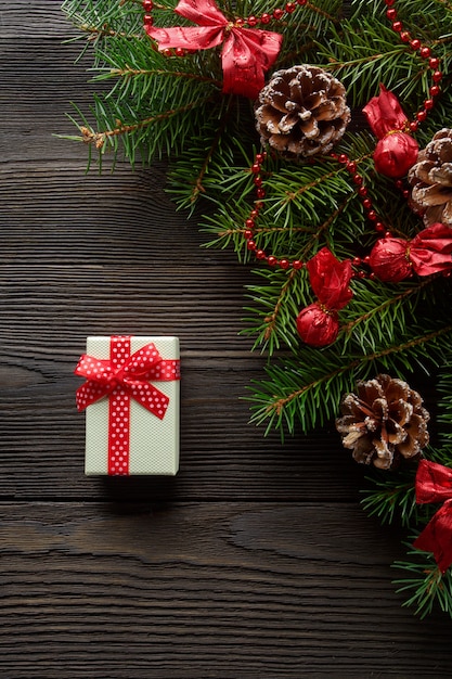 Free photo white box with a red bow on a wooden table with christmas ornament