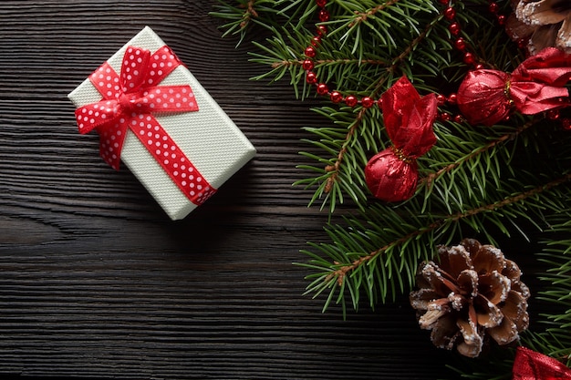 Free photo white box with a red bow on a wooden table with christmas ornament