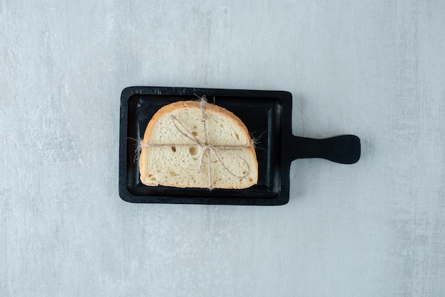 Free photo white bread tied with rope on dark board.