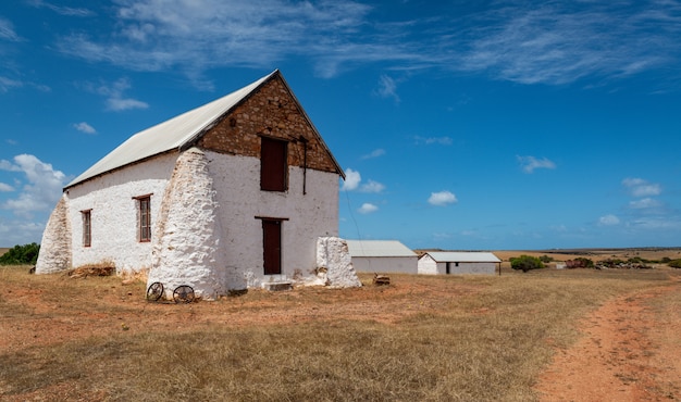 White building in a field of a farm in a rural area under the cloudy sky